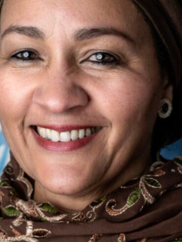 Portrait d’Amina J. Mohammed devant un drapeau des Nations unies