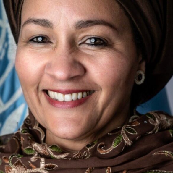 Portrait d’Amina J. Mohammed devant un drapeau des Nations unies