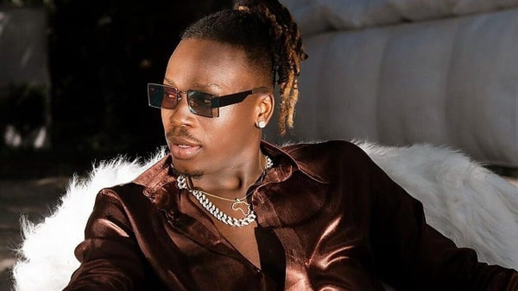 Le chanteur Fireboy DML, lunettes de soleil, en chemise satinée marron