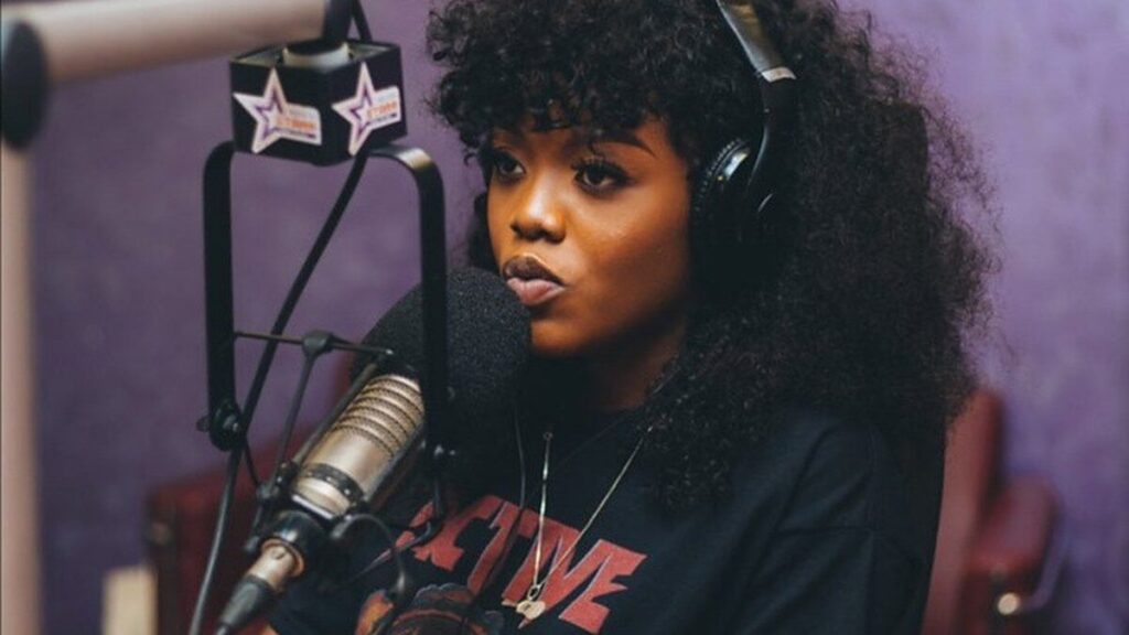 La chanteuse ghanéenne Gyakie au micro d’un studio radio, casque sur les oreilles