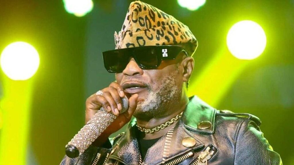 Koffi Olomidé chantant sur scène avec un microphone