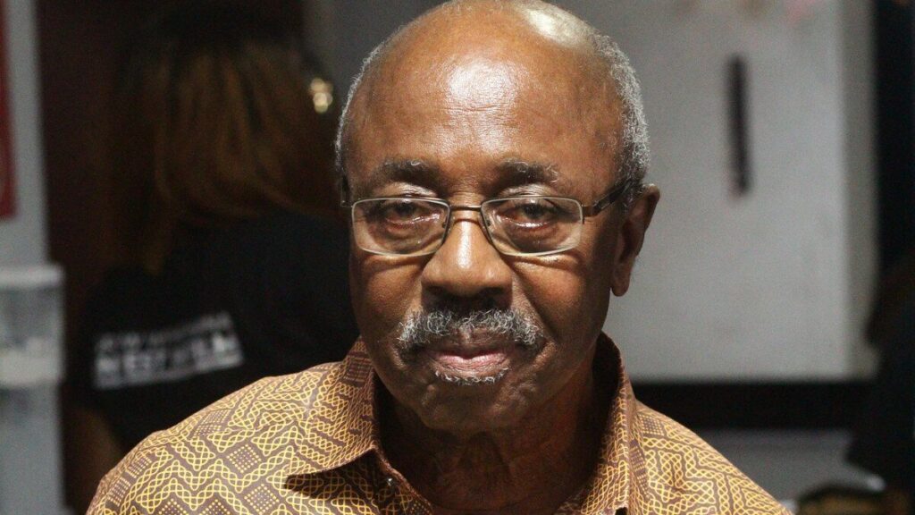 Portrait du cinéaste ghanéen Kwaw Ansah tenant un livre