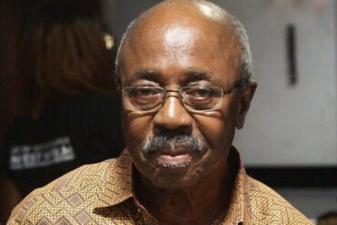 Portrait du cinéaste ghanéen Kwaw Ansah tenant un livre