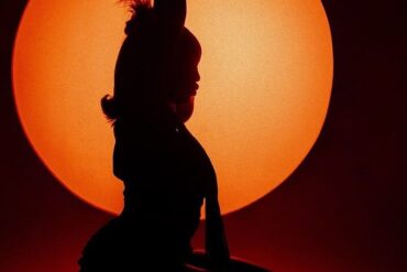 Silhouette d’une chanteuse devant un soleil orange sur le visuel du single Your Body