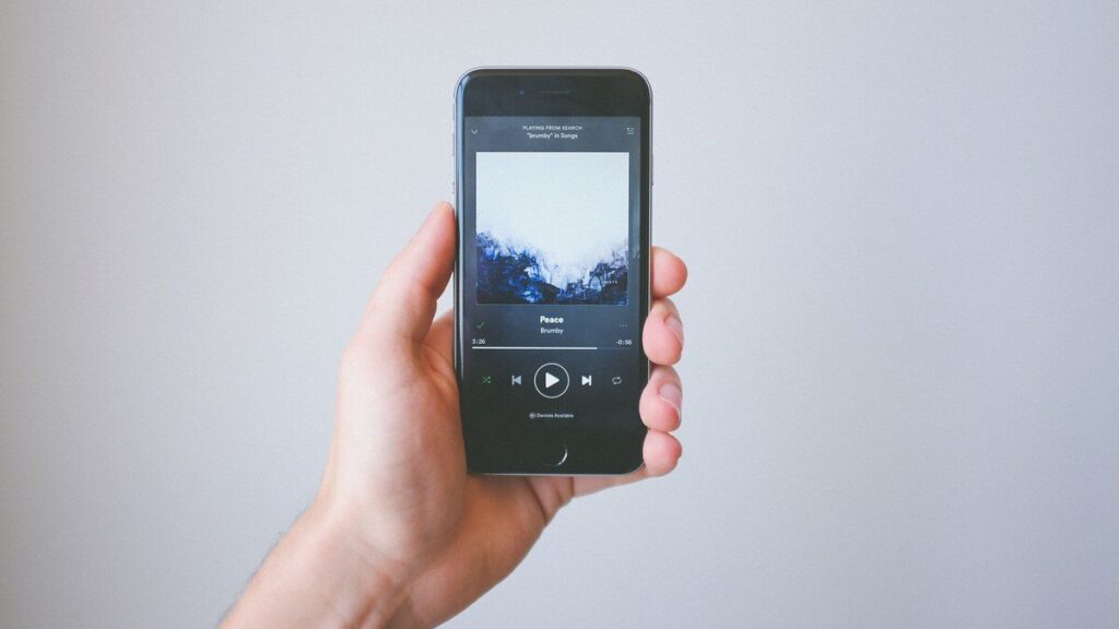 Une main tient un smartphone affichant l’application Spotify